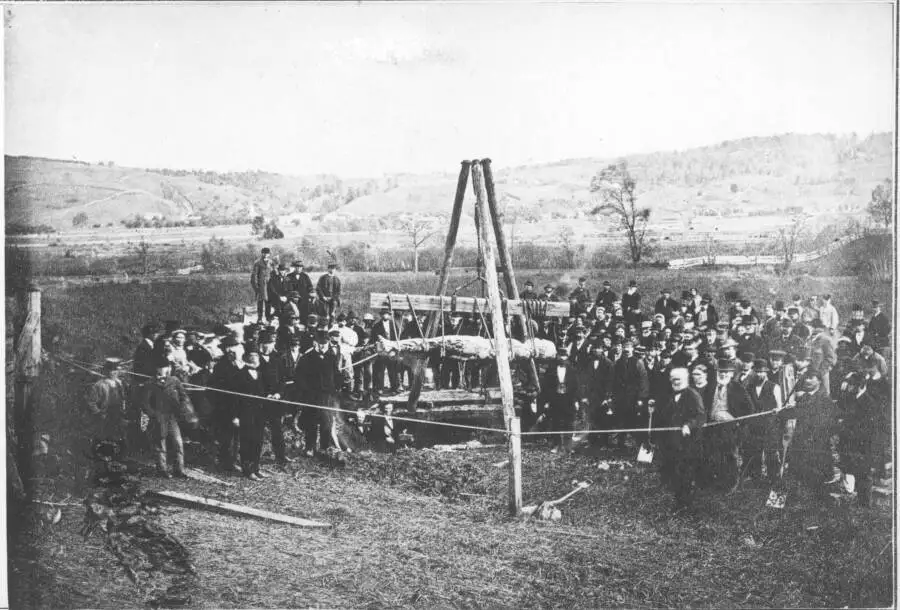 1869年加迪夫巨人被发掘时的历史照片，一群男子围绕在巨大的石化人形周围