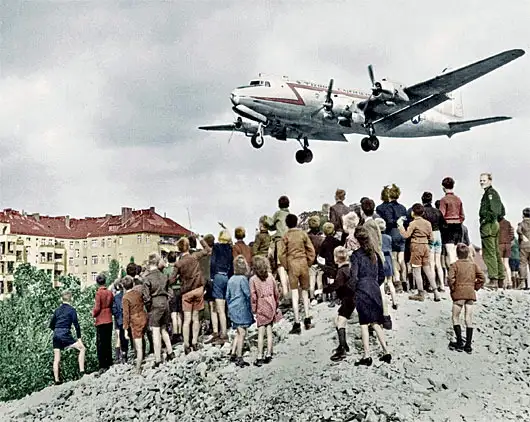 C-54运输机在滕珀尔霍夫机场降落，1948年。柏林市民站在废墟上观看这一历史性场景。