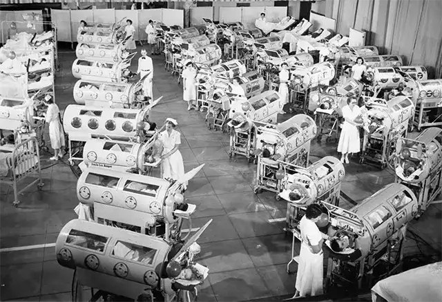 1950年代医院病房中成排的铁肺，每个铁肺中躺着一名脊髓灰质炎患者